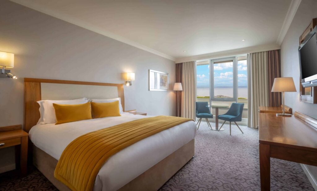 A sea-view bedroom at Salthill Hotel with a king bed and seating beside the bay-facing window